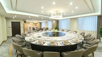 Un salón de conferencias con una mesa redonda, sillas y una araña.