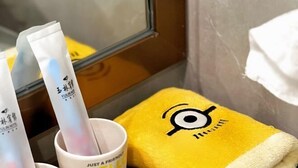 A bathroom with a yellow towel, a white cup, and two tubes of cream. - Yulin Hotel (Yulin)