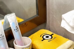Un bagno con un asciugamano giallo, una tazza bianca e due tubetti di crema.