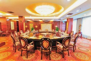 Un salón de conferencias con una mesa redonda, sillas y una araña.