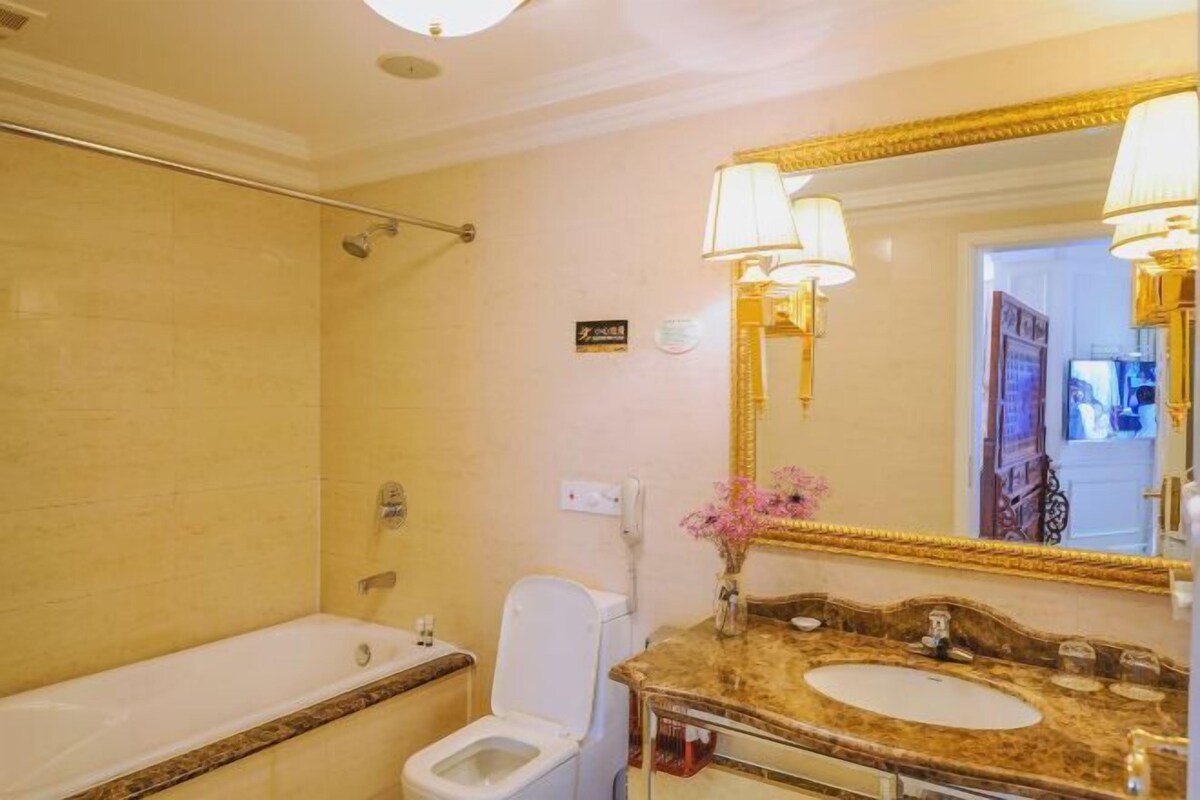 Un bagno con vasca, servizi igienici e un mobile lavabo con un grande specchio e due lampade a parete.