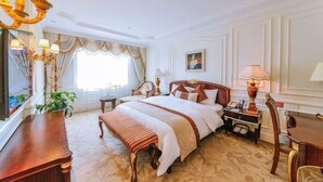 A hotel room with a large bed, a desk, a chair, a lamp, a plant, and a painting on the wall. - Yulin Hotel (Yulin)