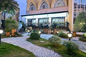A hotel with a modern facade, outdoor seating, and a well-maintained garden area. - Yulin Hotel (Yulin)