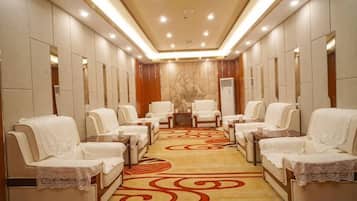 A spa room with multiple massage chairs, a patterned carpet, and a wall-mounted massage table.