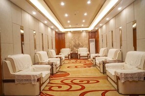A spa room with multiple massage chairs, a patterned carpet, and a wall-mounted massage table. - Yulin Hotel (Yulin)