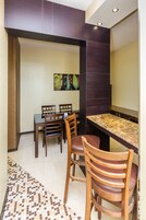 Un comedor con mesa y sillas, un adorno en la pared y un suelo estampado.