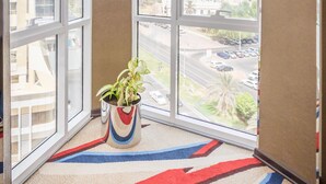 Une pièce d’angle avec de grandes fenêtres, une moquette colorée et une plante en pot.