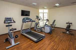 Un gimnasio con cintas de correr, elípticas y un banco.