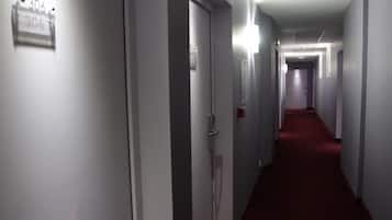 A long, narrow hallway with doors on one side and a red carpet.