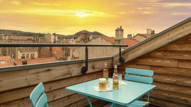 A rooftop terrace with a table, chairs, and bottles of beer. - Urban Style Hotellerie du Cheval Noir (Saint-Etienne)