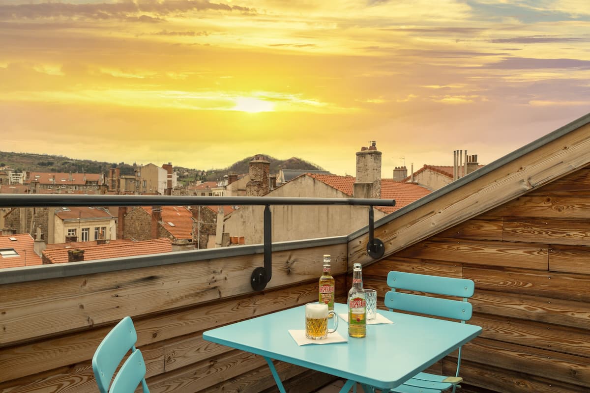 A rooftop terrace with a table, chairs, and bottles of beer.