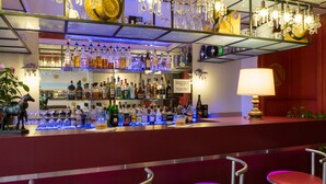 A bar area with multiple liquor bottles, a mirror, and bar stools. - Urban Style Hotellerie du Cheval Noir (Saint-Etienne)