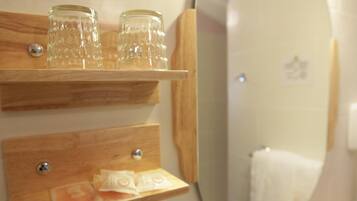 A wooden shelf with two clear glass jars and a wooden tray with tissue paper.