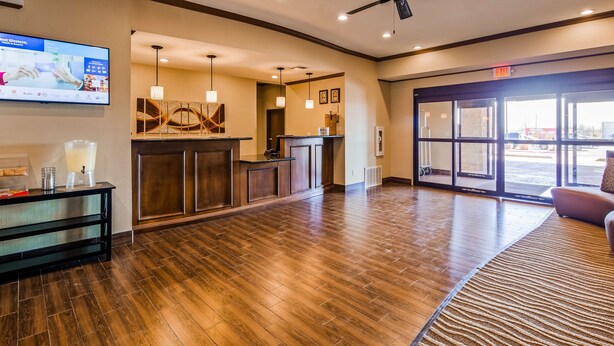 A reception area with a wooden floor, a reception desk, a large window, and a television mounted on the wall. - Best Western Plus Seminole Hotel & Suites (Seminole)