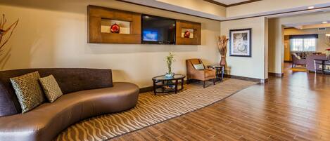 A modern living room with a curved sofa, a coffee table, and a television mounted on the wall.