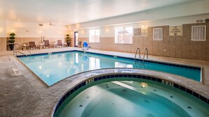 An indoor swimming pool with clear water, a diving board, and a lounge area with chairs and a small table. - Best Western Plus Seminole Hotel & Suites (Seminole)
