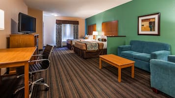 Ein Hotelzimmer mit einem Bett, einem blauen Sofa, einem Holztisch, einem Fernseher und einem Schreibtisch mit Stühlen.