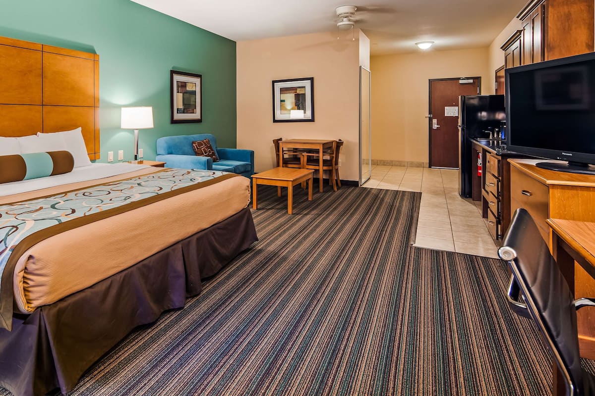 A hotel room with a large bed, a desk, a television, and a seating area.