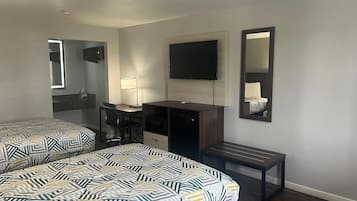 A hotel room with two beds, a desk, a chair, a TV, and a mirror.