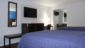 A hotel room with a large bed, a desk with a chair, a flat-screen TV mounted on the wall, a lamp, and a mirror. - Motel 6 Saint George, SC – I-95 (St. George)
