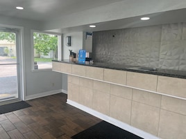 A reception area with a counter, a door leading outside, and a patterned wall.