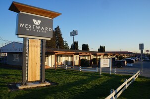 Un motel con un cartel para Westward Inn & Suites, un estacionamiento y un edificio con un área de estar al aire libre techada.