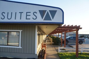 Un edificio con un letrero que dice "SUITES" y un área exterior cubierta con bancos.
