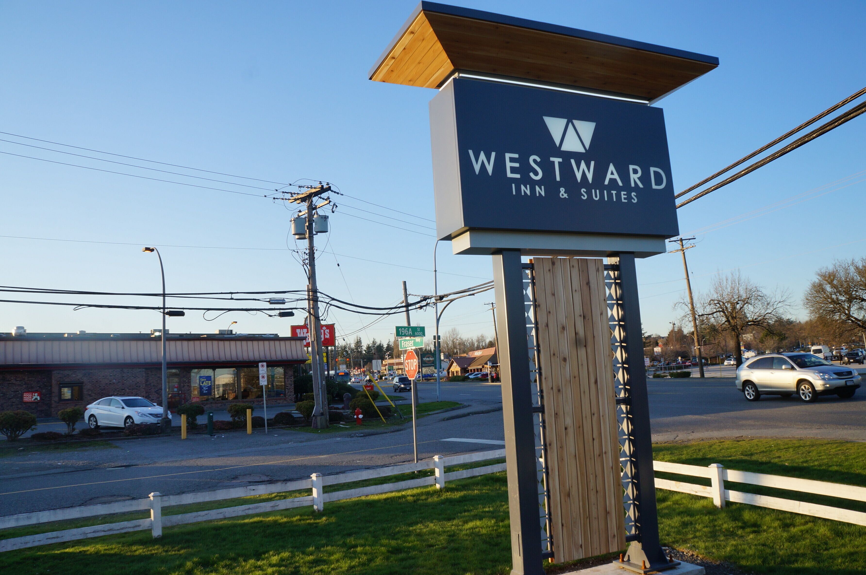 A Westward Inn & Suites sign at a roadside intersection with a stop sign and a gas station in the background.