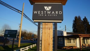 Señal de Westward Inn & Suites, con una estructura de madera y un cielo azul despejado al fondo.