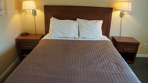 Habitación de hotel con una cama grande, dos mesitas de noche y dos lámparas de pared.