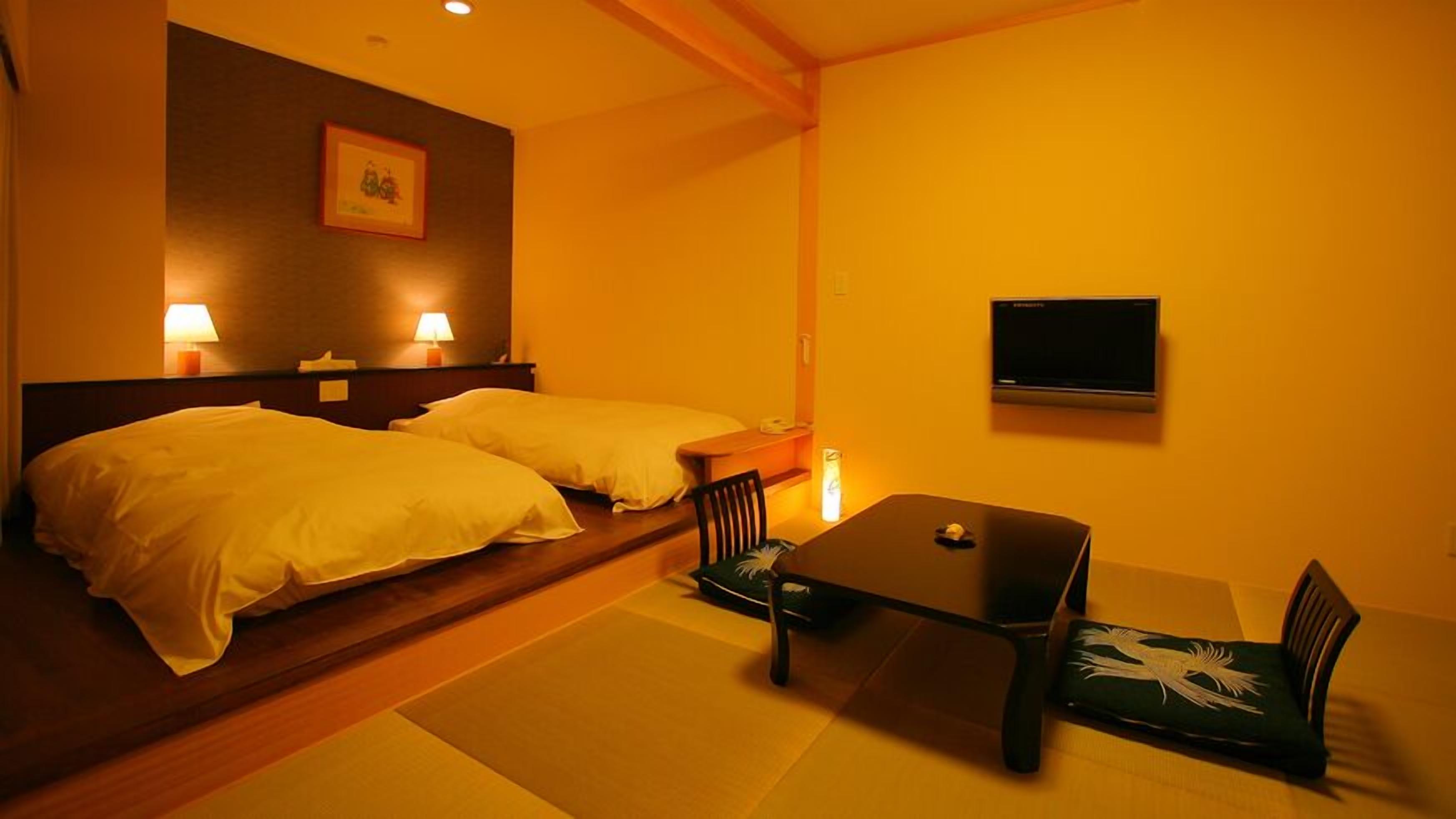 A hotel room with two beds, a small table, chairs, a TV, and a picture on the wall.