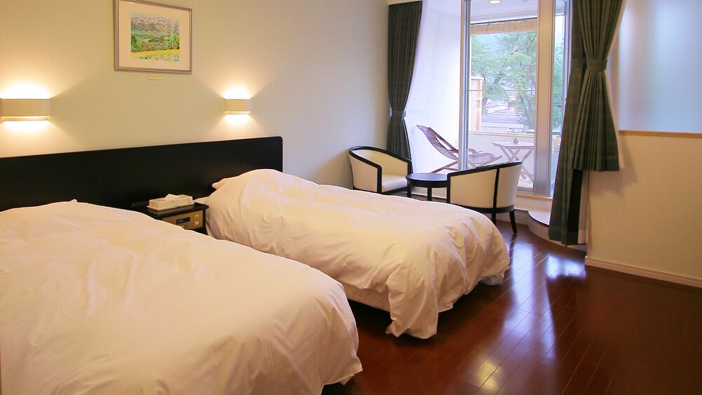 Une chambre d’hôtel avec deux lits, un bureau, une chaise et un balcon avec vue.