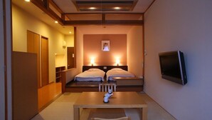 A hotel room with a wooden table, two beds with white linens, a flat-screen TV mounted on the wall, and a framed picture above the beds. - Nozawa Grand Hotel (Nozawaonsen)