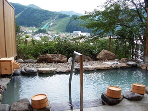 A traditional Japanese onsen with a view of a town and mountains in the background. - Nozawa Grand Hotel (Nozawaonsen)