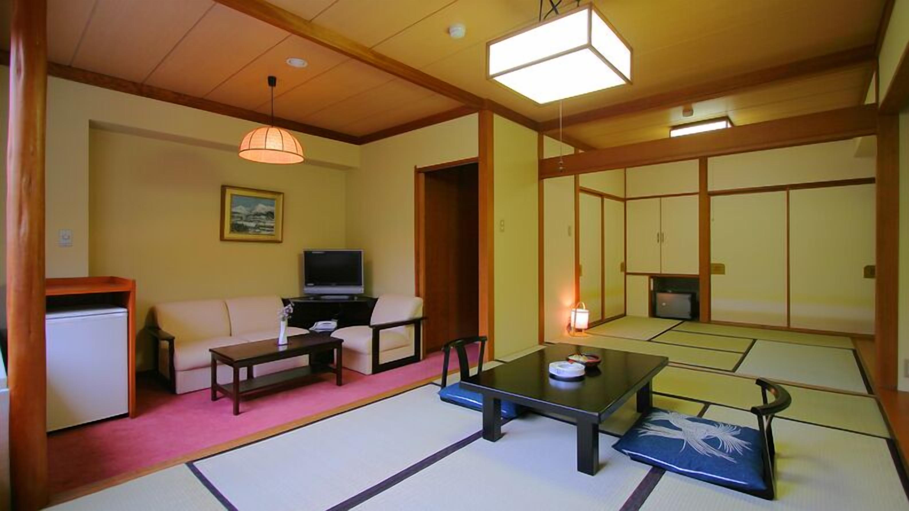 Une pièce de style japonais traditionnel, avec un sol recouvert de tatamis, une table basse, un canapé, un téléviseur et des portes coulissantes.