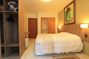 Una camera d'albergo con un letto, un armadio, un quadro appeso al muro e l'ingresso del bagno.