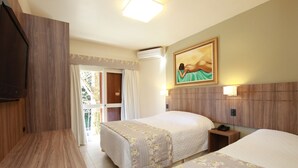 A hotel room with two beds, a wooden wardrobe, a painting on the wall, and a balcony with curtains. - Pousada Águia Branca (Gramado)