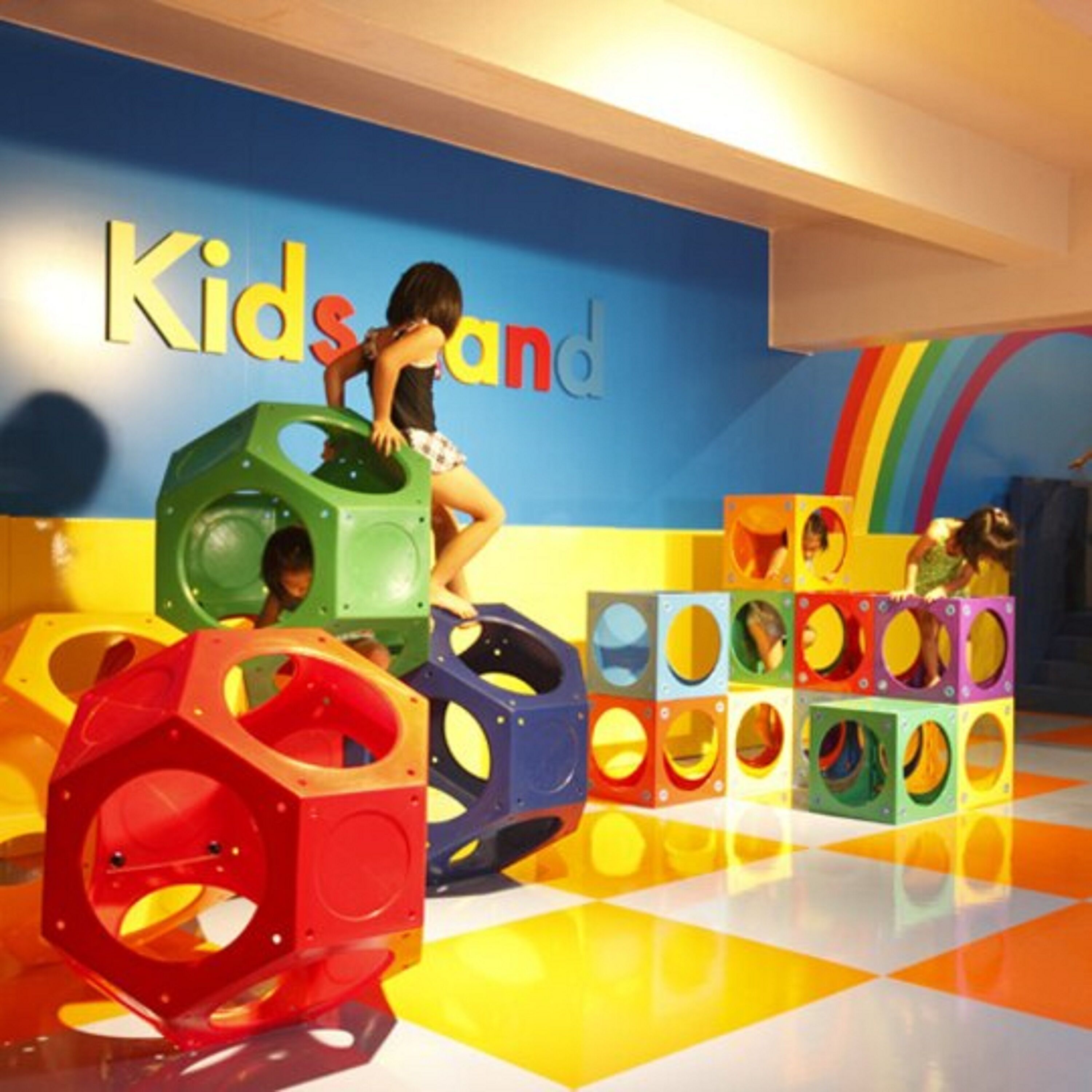 A children's play area with colorful play structures and a wall with the text "Kidsland".