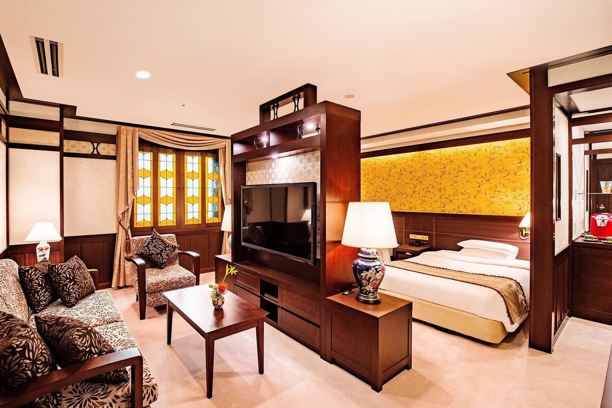 Ein Hotelzimmer mit Bett, Fernseher, Sofa, Couchtisch und Schreibtisch.