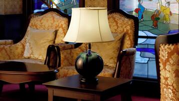 A lamp on a table, a sofa, and a stained glass window in a room.