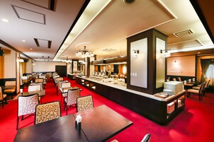 Un vestíbulo de hotel con alfombra roja, varias mesas de comedor y una zona de bar central.