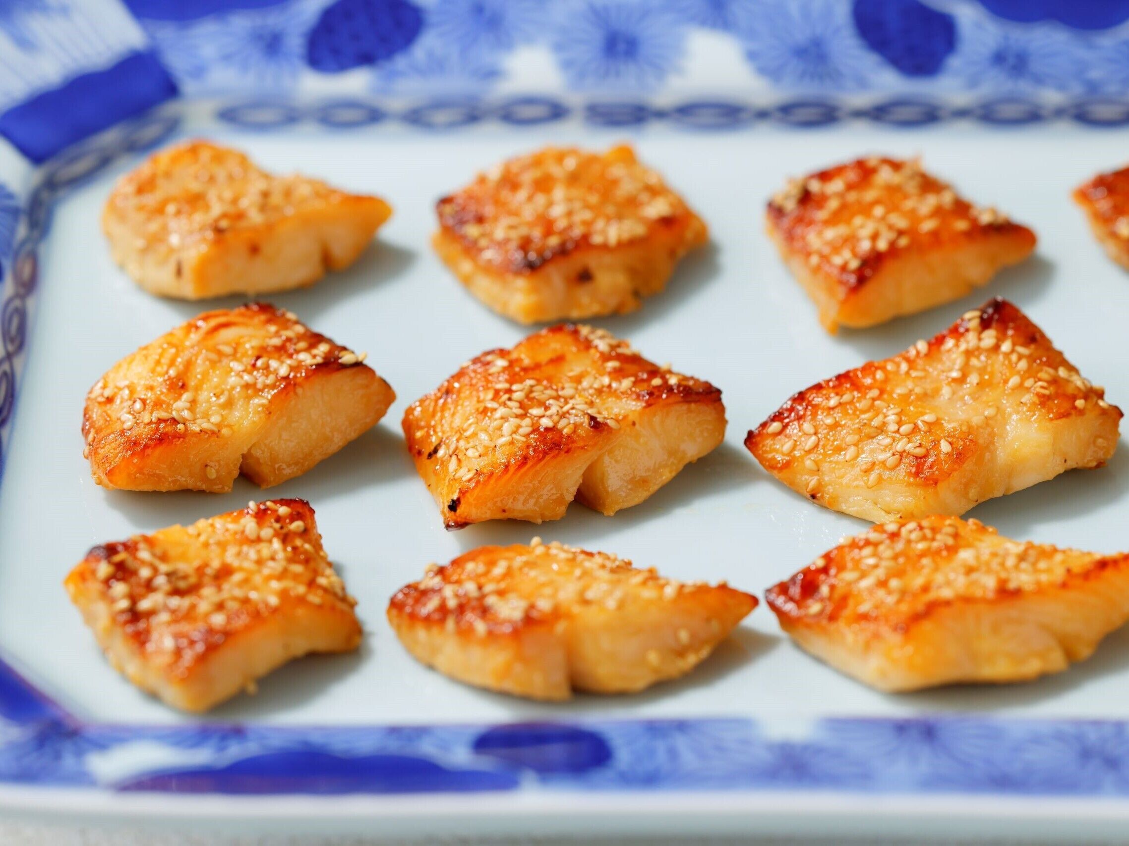 A plate of triangular food items topped with sesame seeds.