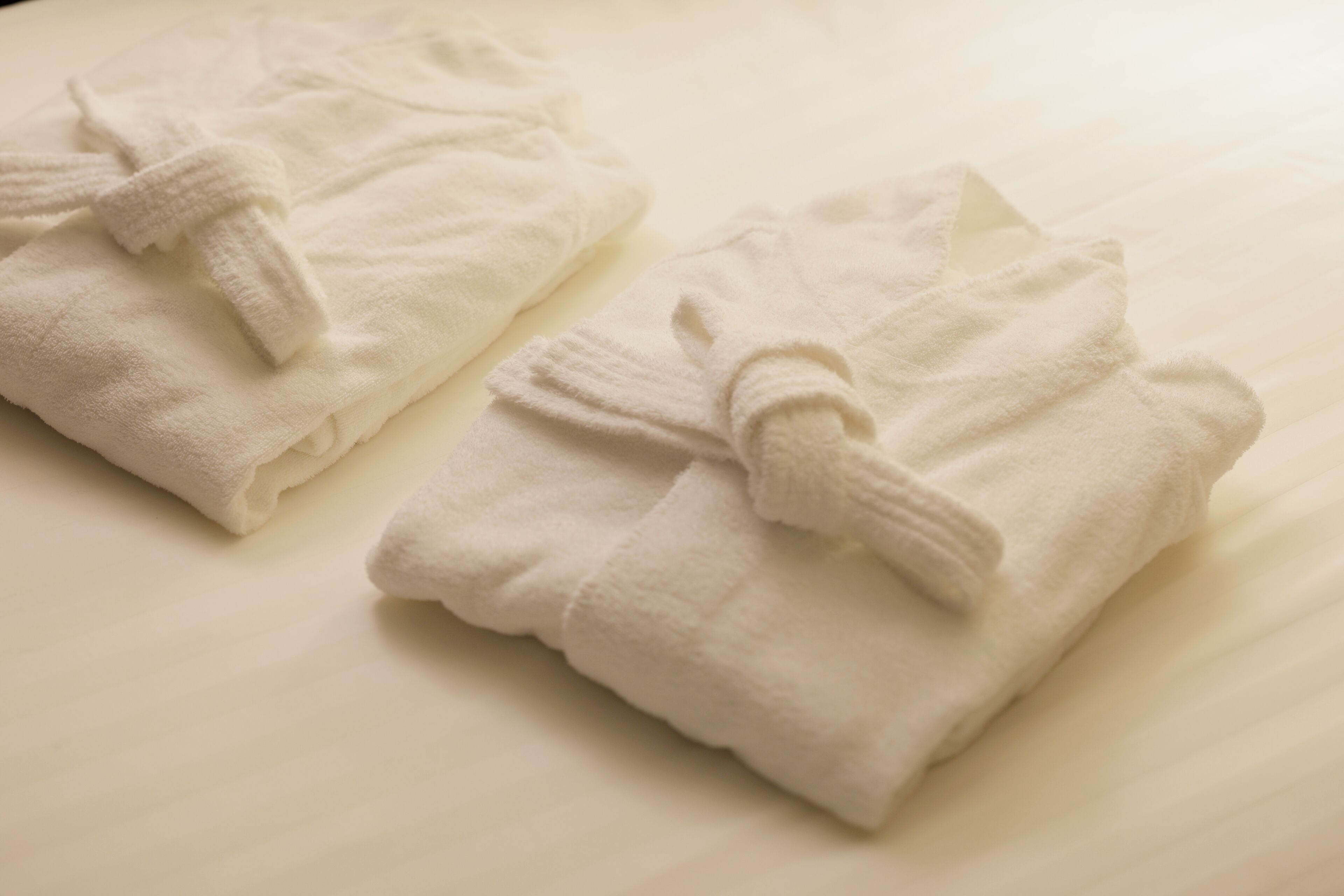 Two neatly folded white towels on a bed.
