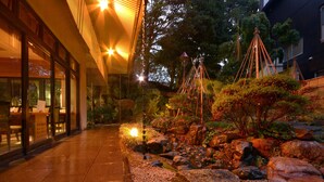 A pathway leading to a building with large windows and a well-maintained garden with rocks and plants.