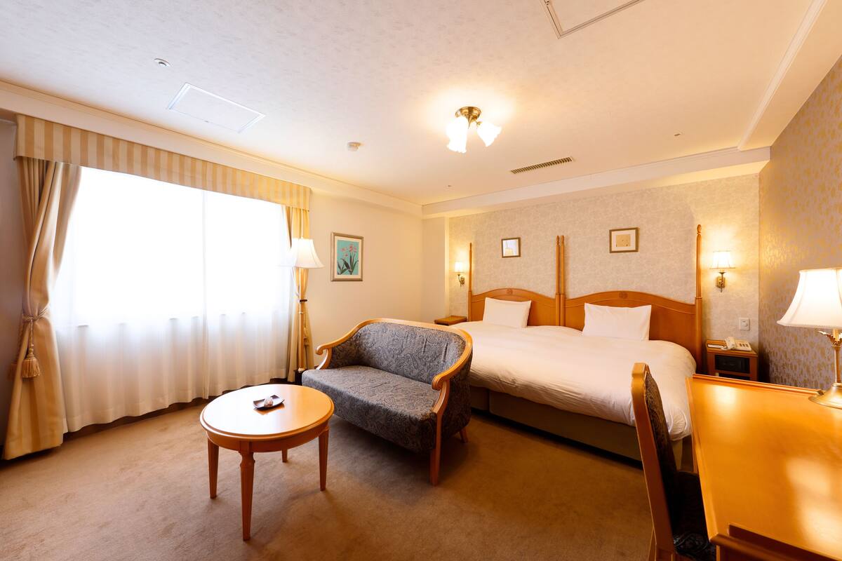 Ein Hotelzimmer mit Bett, Sofa, kleinem Tisch und Lampe.