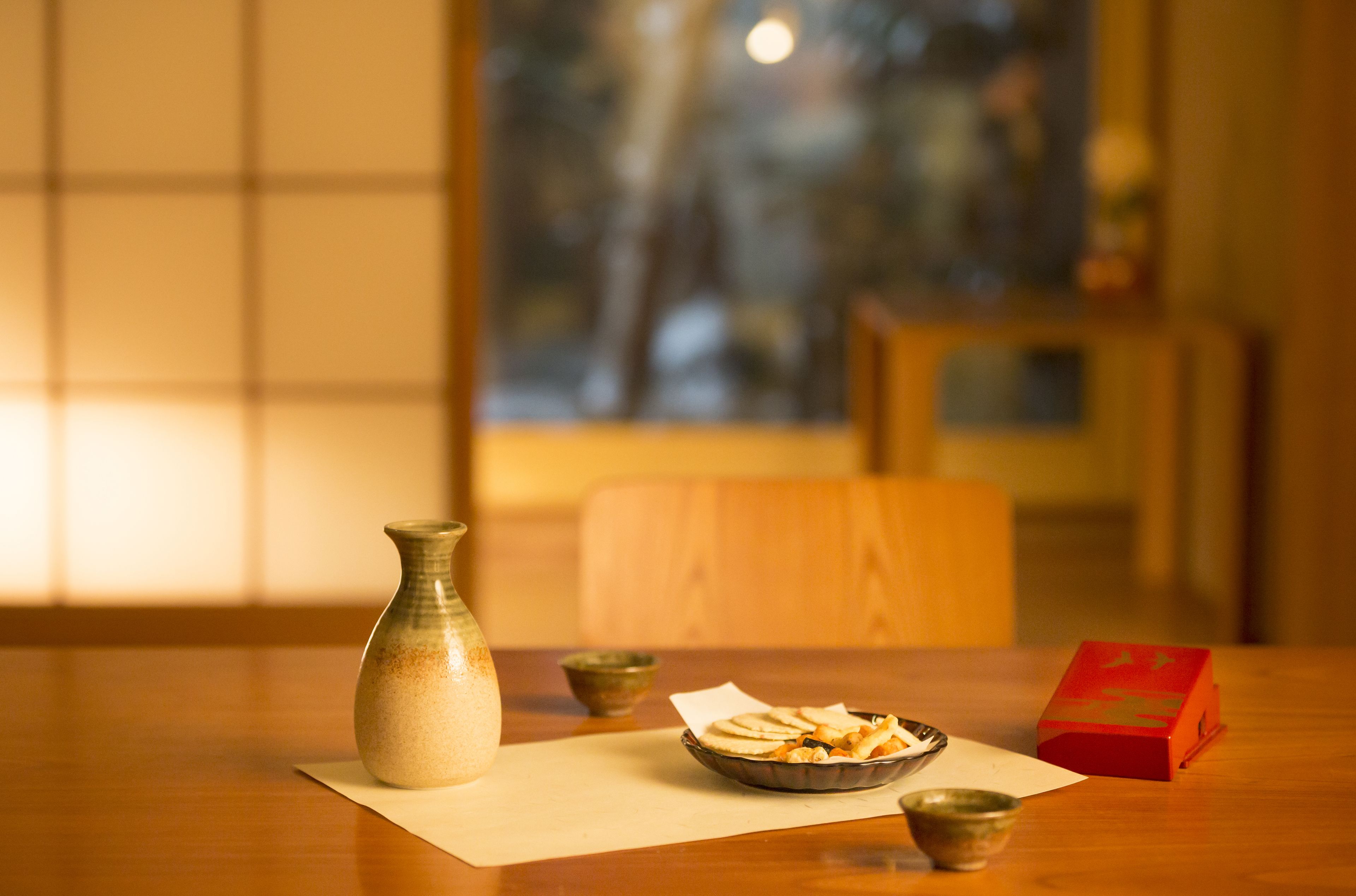 A wooden table with a vase, a bowl of food, a small bowl, and a red box.