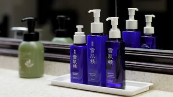 A bathroom counter with a white soap dish holding several bottles of skincare products.