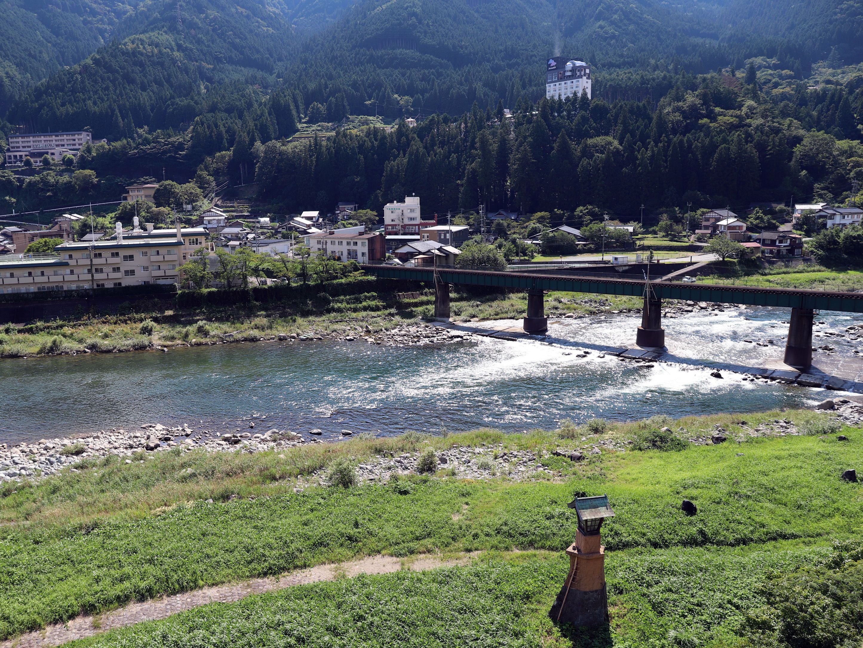 A bridge over a river with buildings and a hill in the background.