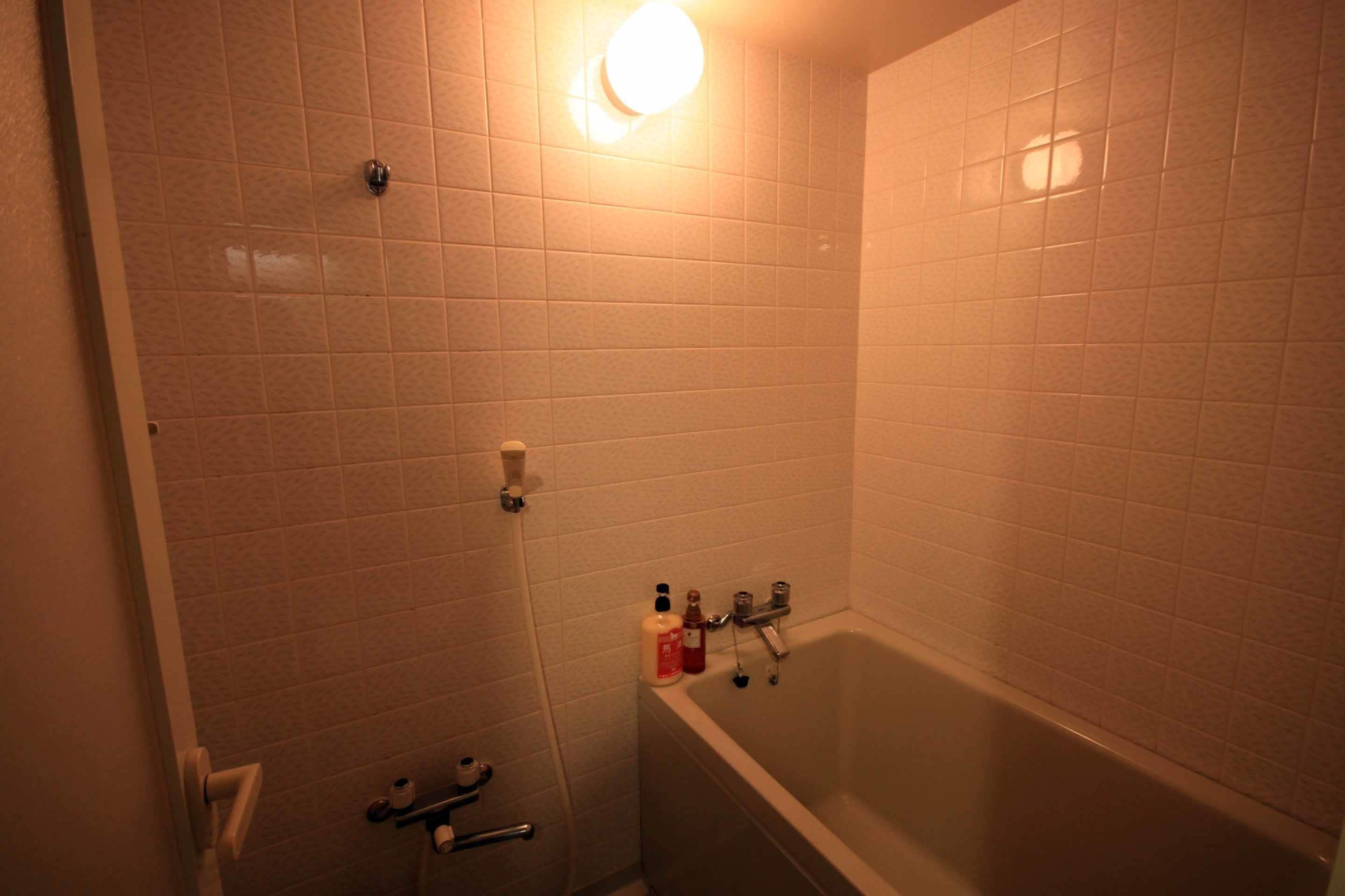 Un baño con bañera, inodoro y ducha. Hay artículos de aseo en la pared.