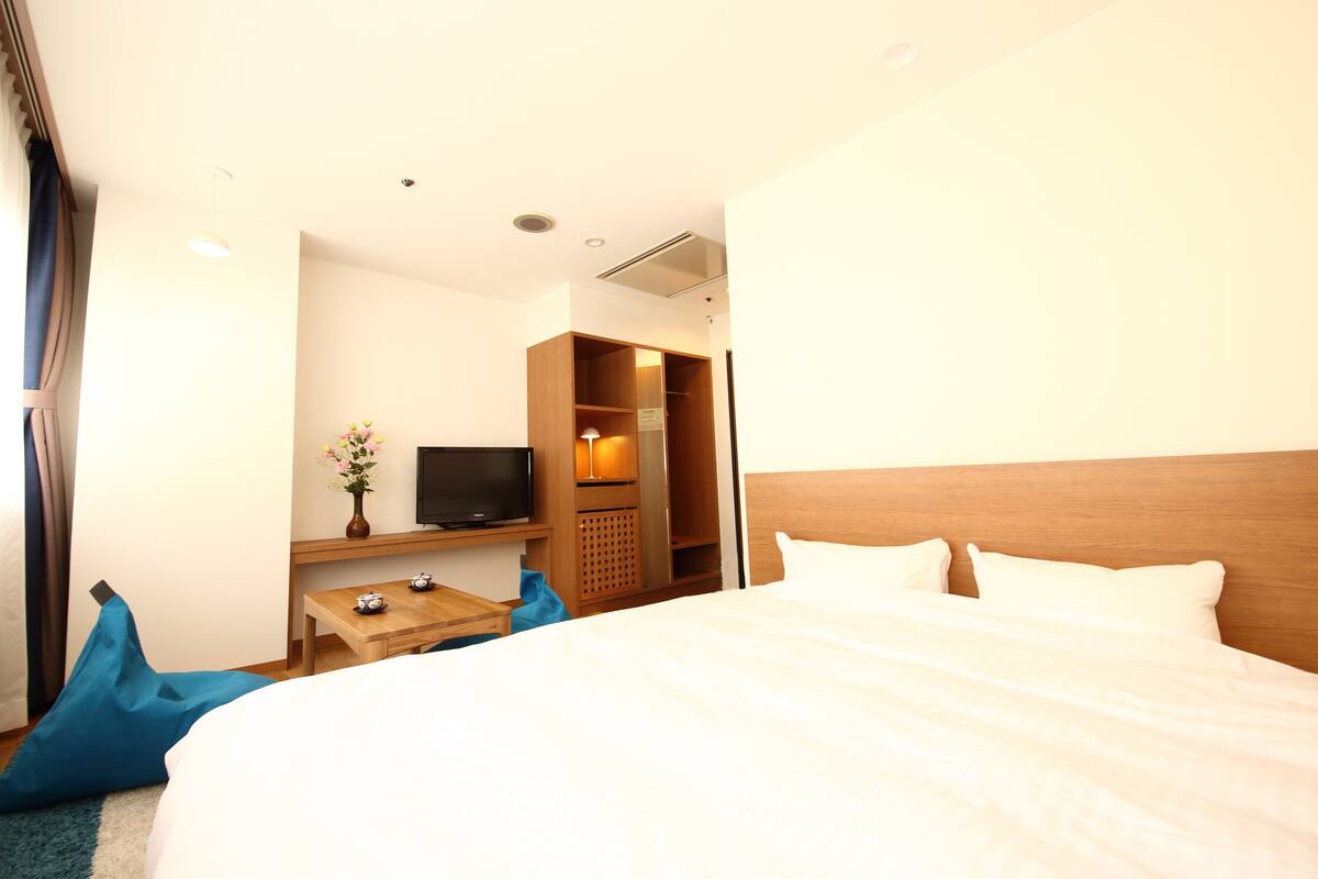 Ein Hotelzimmer mit Bett, Fernseher, Schreibtisch mit Lampe und Kleiderschrank.